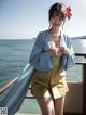 A woman in a blue kimono standing on a boat by the water.