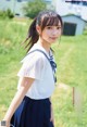 A young woman in a school uniform standing in a field.