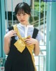 A woman in a school uniform holding a yellow scarf.