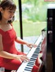 A woman in a red dress playing a piano.