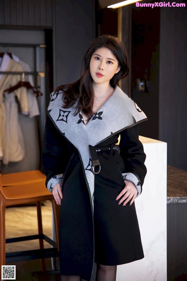 A woman in a black and white coat standing in a room.