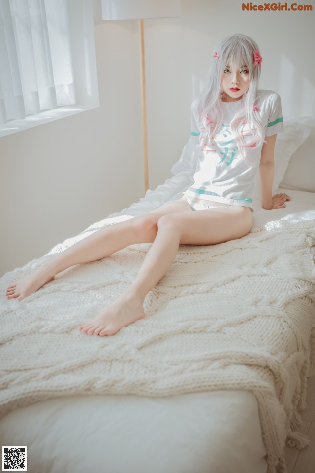 A woman sitting on a bed with her legs crossed.