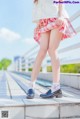 A woman in a white shirt and pink plaid skirt is standing on a bridge.