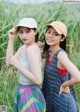 Two young women standing next to each other in a field.