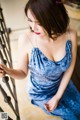 A woman in a blue dress leaning against a railing.